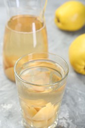 Photo of Delicious quince drink and fresh fruits on grey table, closeup