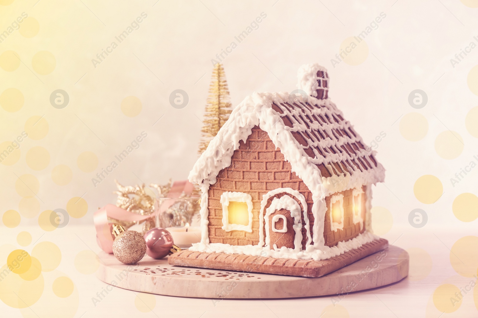Image of Beautiful gingerbread house decorated with icing and Christmas baubles on table