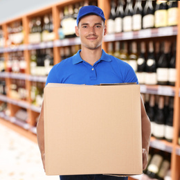 Man wearing uniform with cardboard box in store. Wholesale market