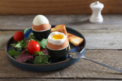 Delicious breakfast with soft boiled eggs served on wooden table, closeup