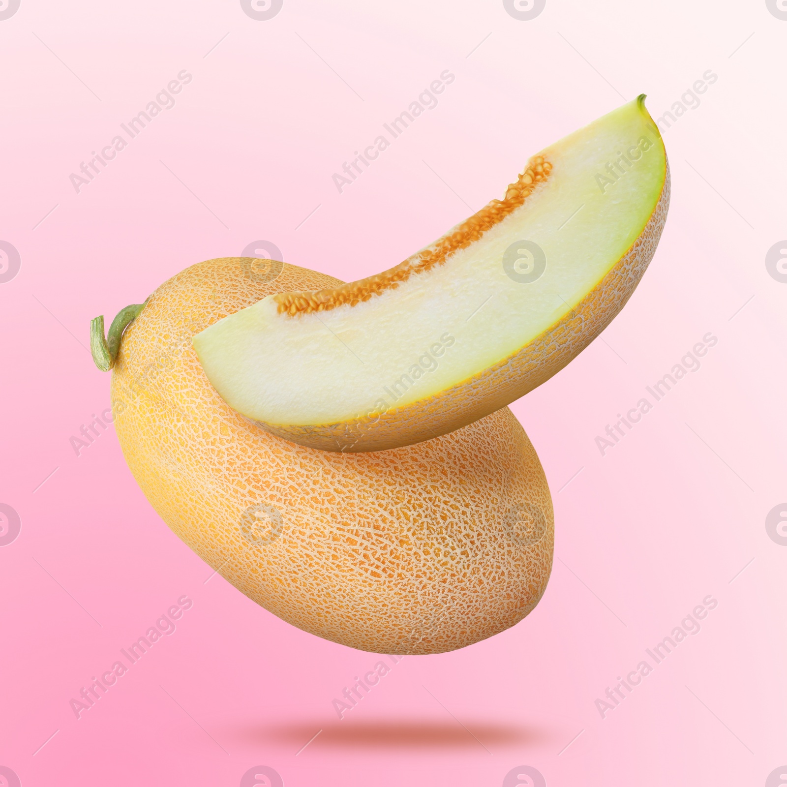 Image of Delicious ripe melons falling on light pink background