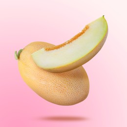 Image of Delicious ripe melons falling on light pink background