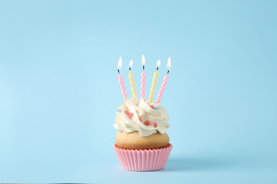 Birthday cupcake with candles on light blue background