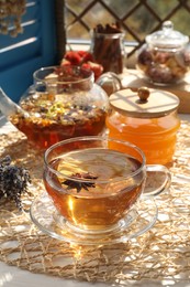 Photo of Aromatic tea with different dry plants and honey on white table