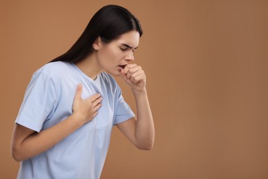 Photo of Woman coughing on brown background, space for text. Cold symptoms