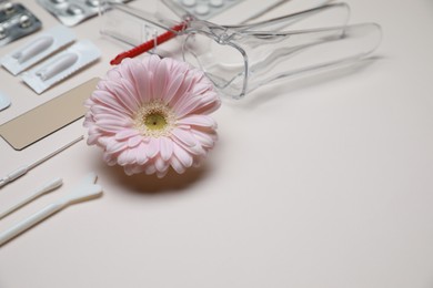 Sterile gynecological tools, pills and gerbera flower on beige background. Space for text