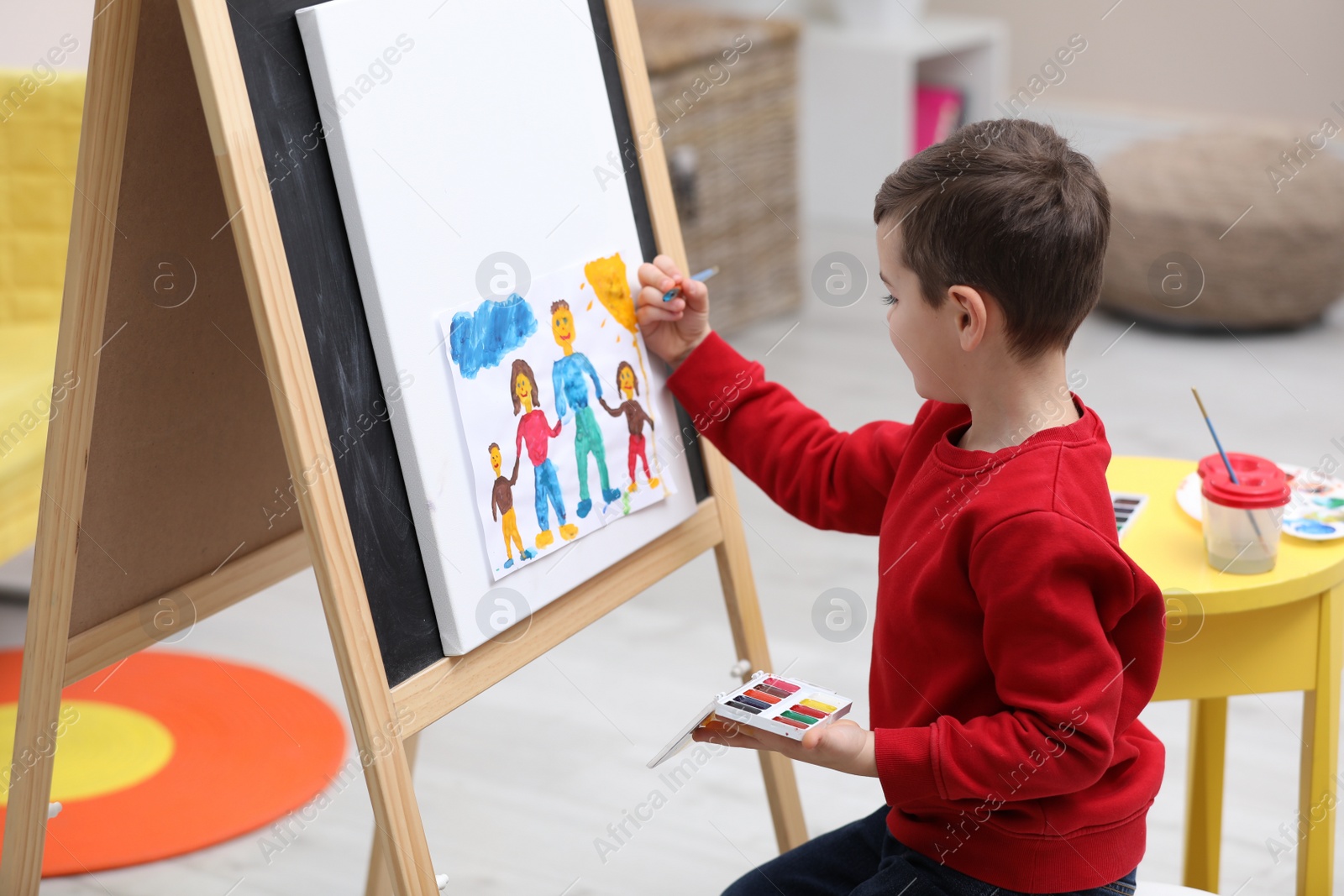 Photo of Little child painting on easel in room