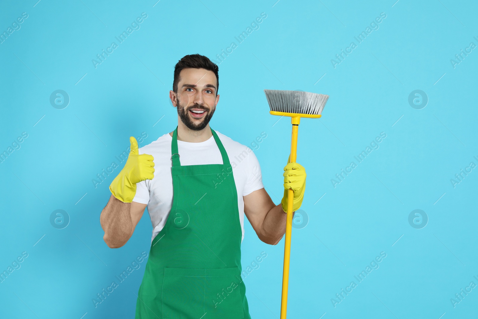 Photo of Man with yellow broom on light blue background