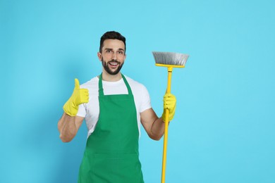 Photo of Man with yellow broom on light blue background
