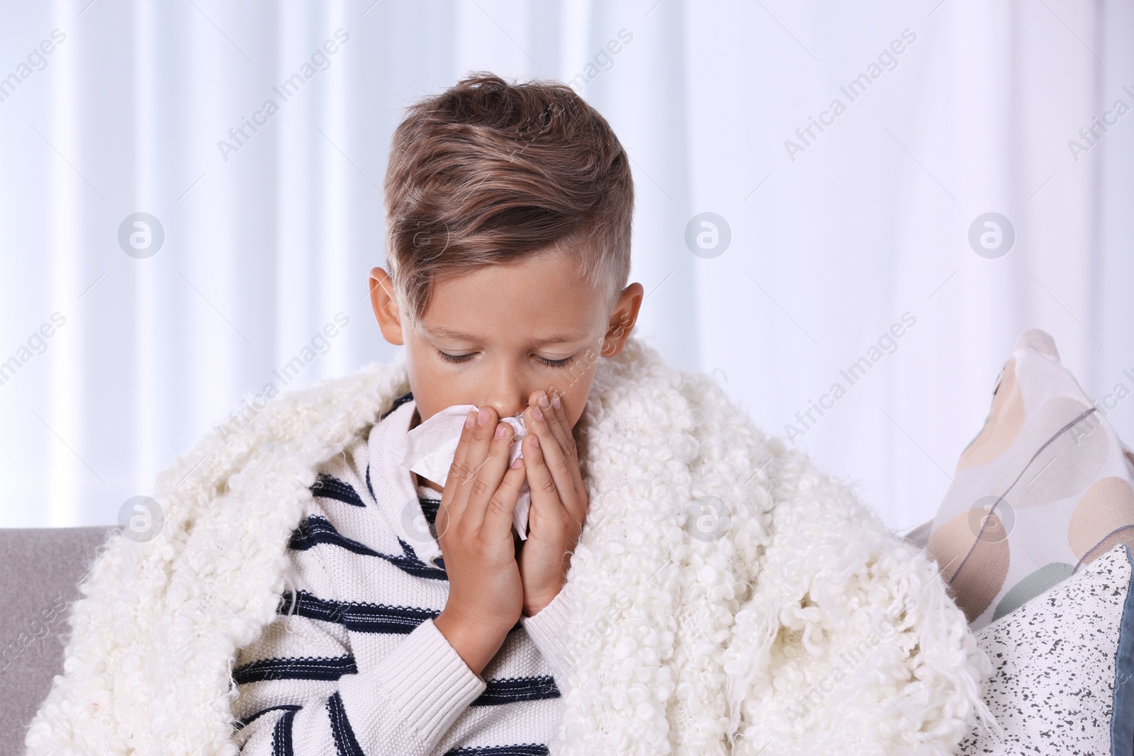 Photo of Ill boy suffering from cough on sofa at home