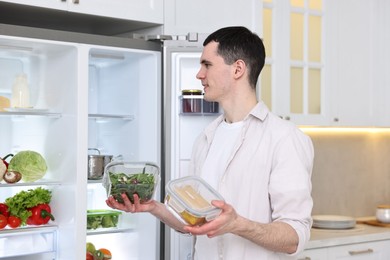 Man holding ketchup near refrigerator in kitchen