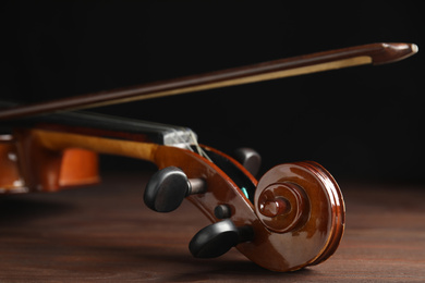 Photo of Classic violin and bow on wooden background, closeup