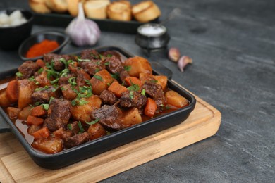 Delicious beef stew with carrots, parsley and potatoes on grey table, closeup. Space for text