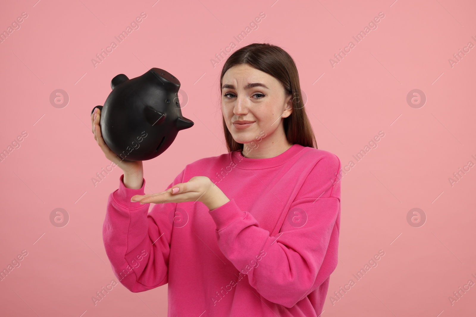 Photo of Sad woman with piggy bank on pink background