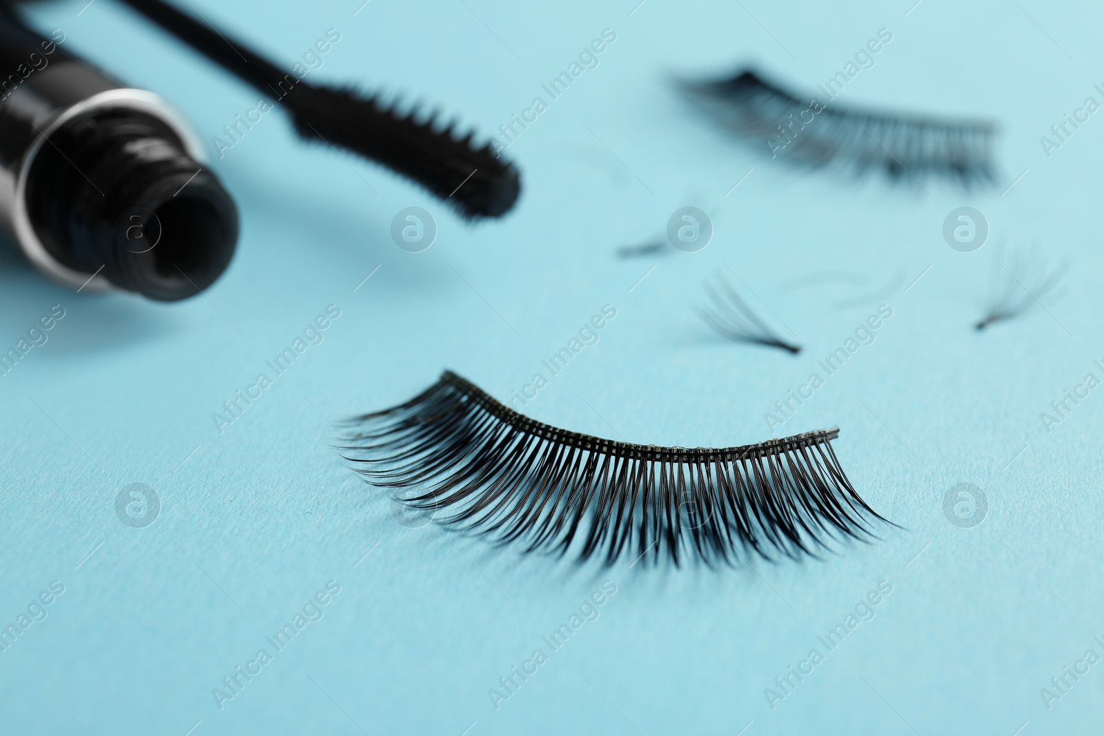 Photo of Mascara and false eyelashes on color background, closeup