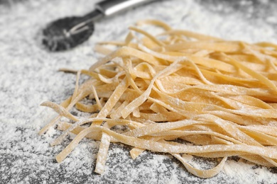 Photo of Uncooked noodles and flour on table, closeup