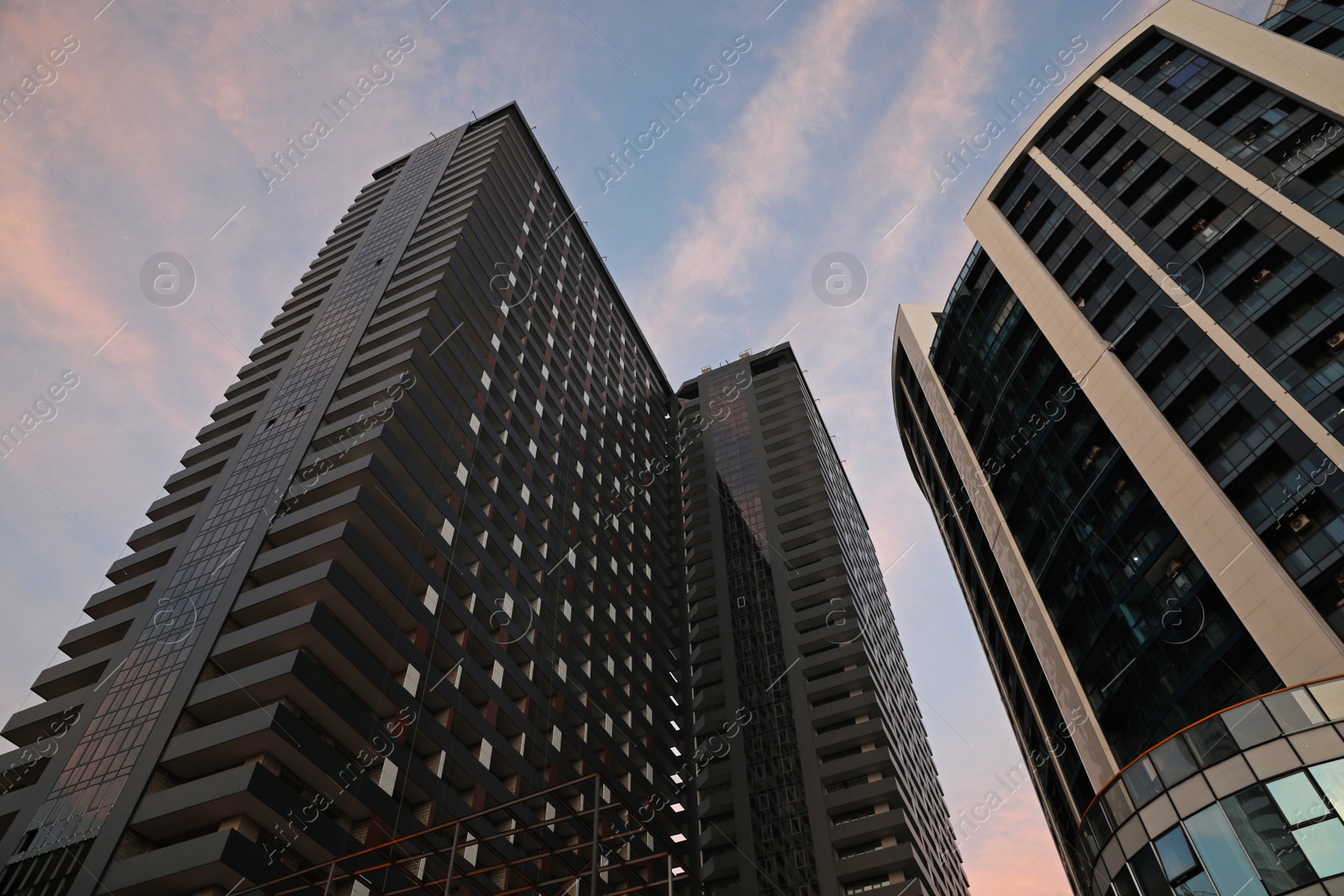 Photo of Beautiful skyscrapers on city street in evening, low angle view