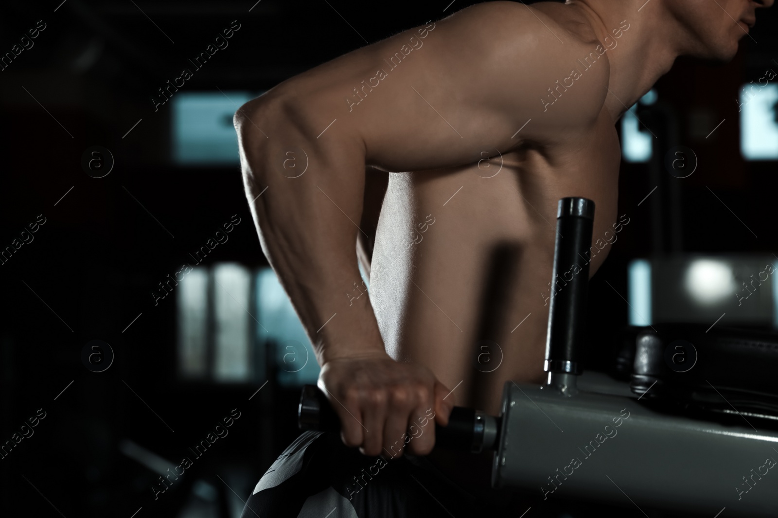 Photo of Strong man working out on parallel bars in modern gym, closeup