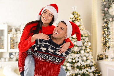 Happy couple in Santa hats having fun at home. Christmas celebration