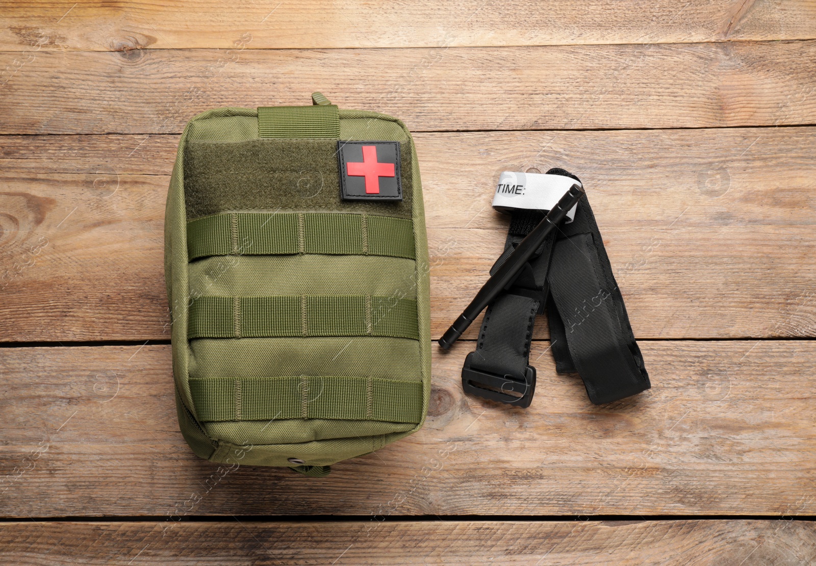 Photo of Military first aid kit and tourniquet on wooden table, flat lay
