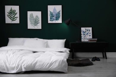 Comfortable bed with stylish white linens near green wall indoors