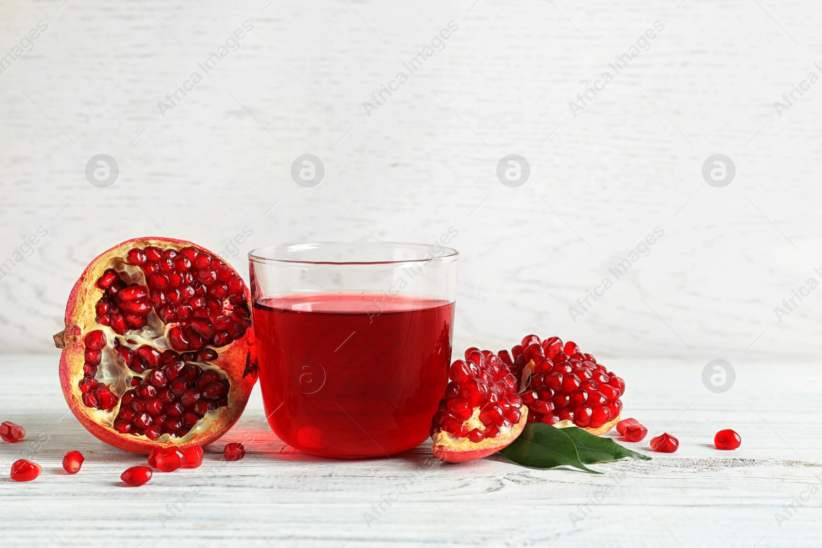 Photo of Glass of pomegranate juice and fresh fruits on wooden table, space for text