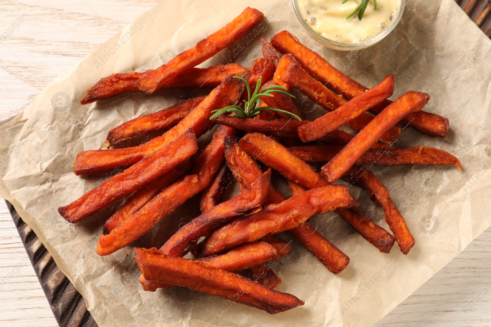 Photo of Board with delicious sweet potato fries and sauce on white wooden table, closeup