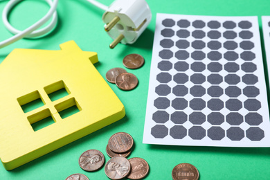 Photo of Solar panels, house model and coins on green background
