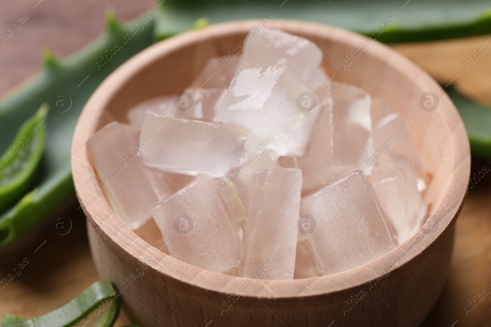 Photo of Aloe vera gel and slices of plant on table, closeup