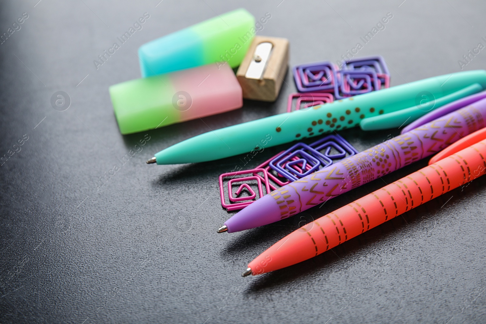 Photo of Different colorful stationery on chalkboard surface. Back to school