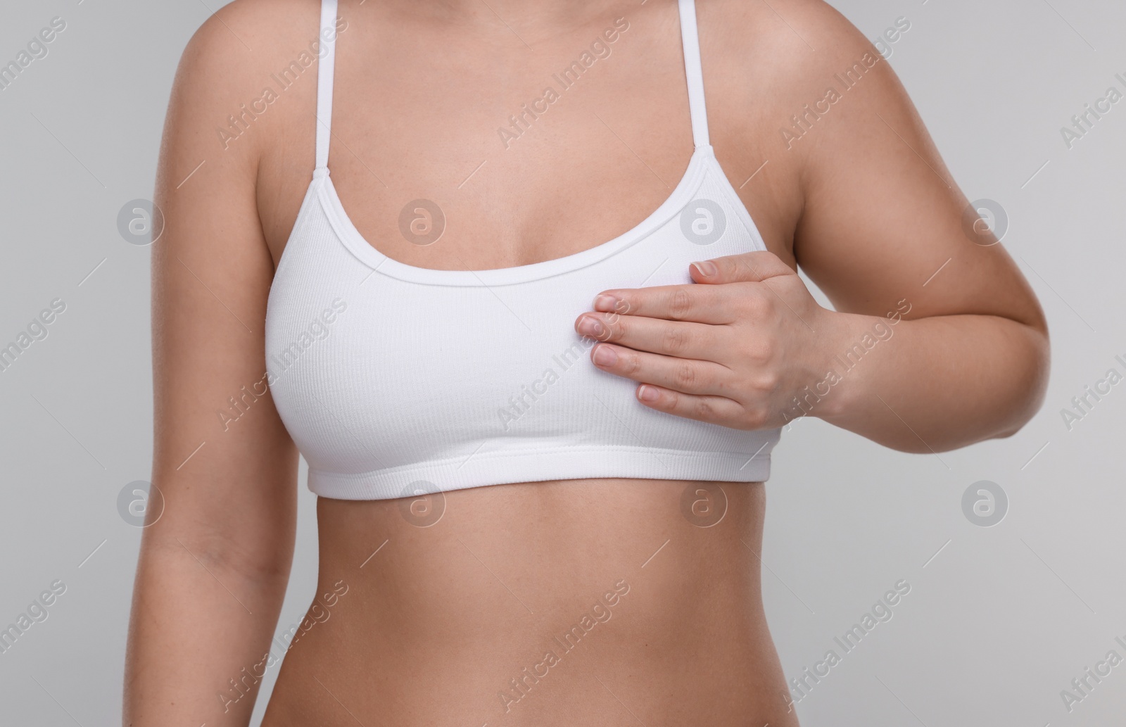 Photo of Mammology. Woman doing breast self-examination on light grey background, closeup