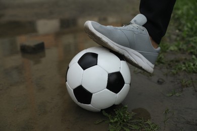 Photo of Man with soccer ball in puddle outdoors, closeup