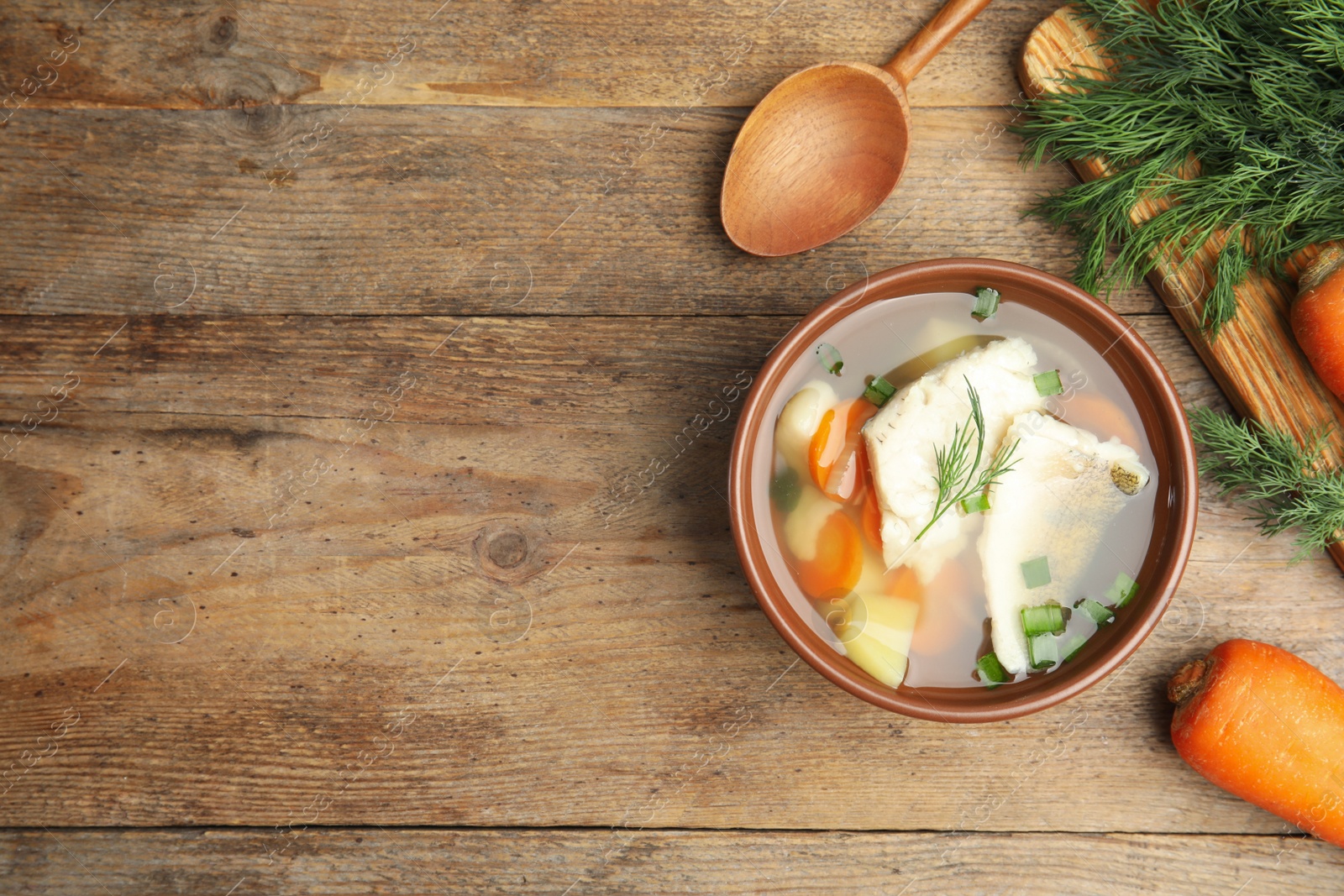 Photo of Delicious fish soup served on wooden table, flat lay. Space for text