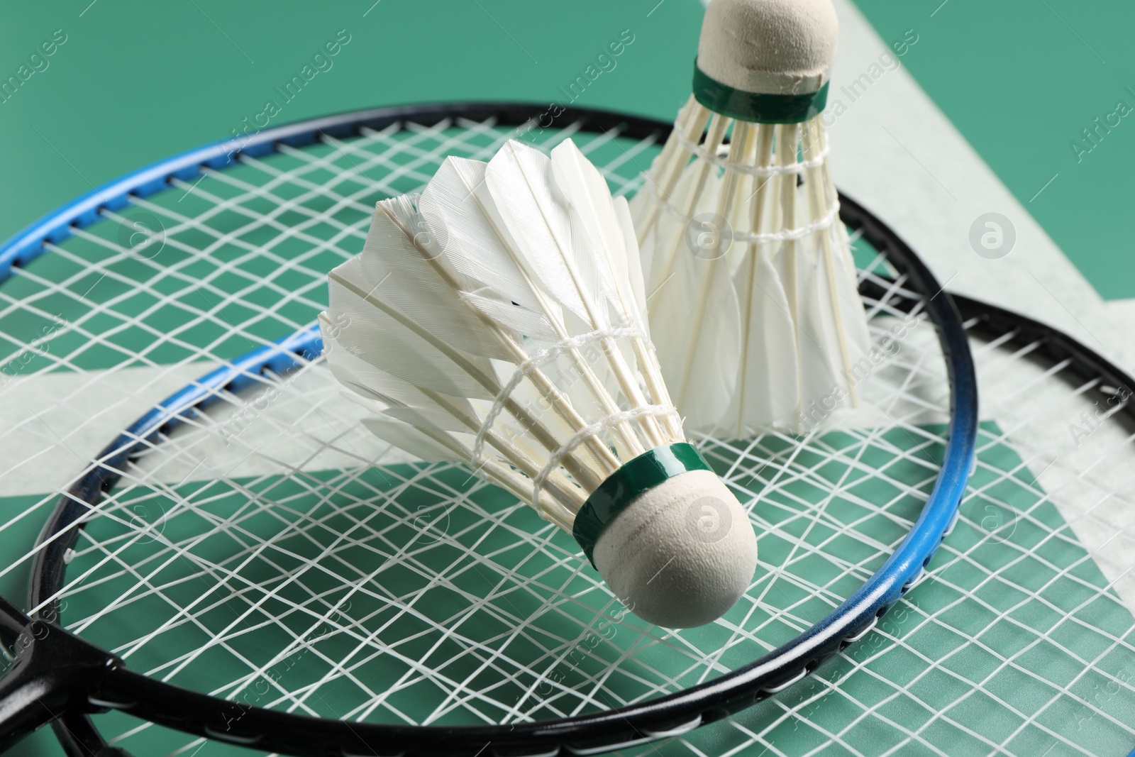 Photo of Feather badminton shuttlecocks and rackets on green table, closeup