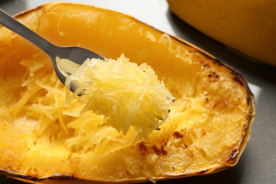 Photo of Fork with flesh of cooked spaghetti squash on blurred background, closeup