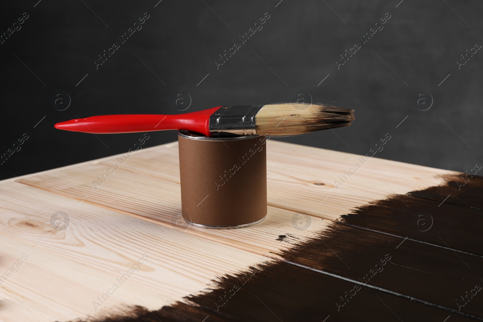 Photo of Brush and can of wood stain on wooden surface