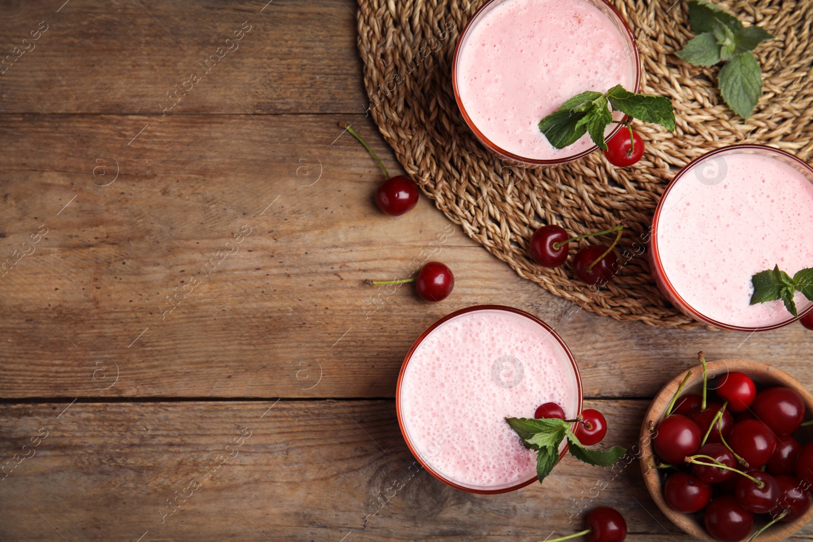 Photo of Tasty fresh milk shakes with cherries on wooden table, flat lay. Space for text