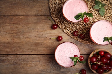 Photo of Tasty fresh milk shakes with cherries on wooden table, flat lay. Space for text