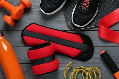 Photo of Red weighting agents and sport equipment on grey wooden table, flat lay