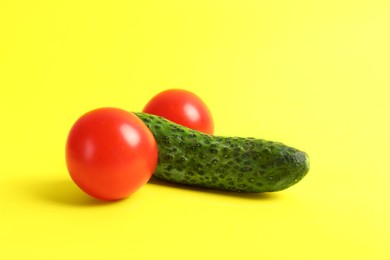 Photo of Cucumber and tomatoes symbolizing male genitals on yellow background. Potency concept