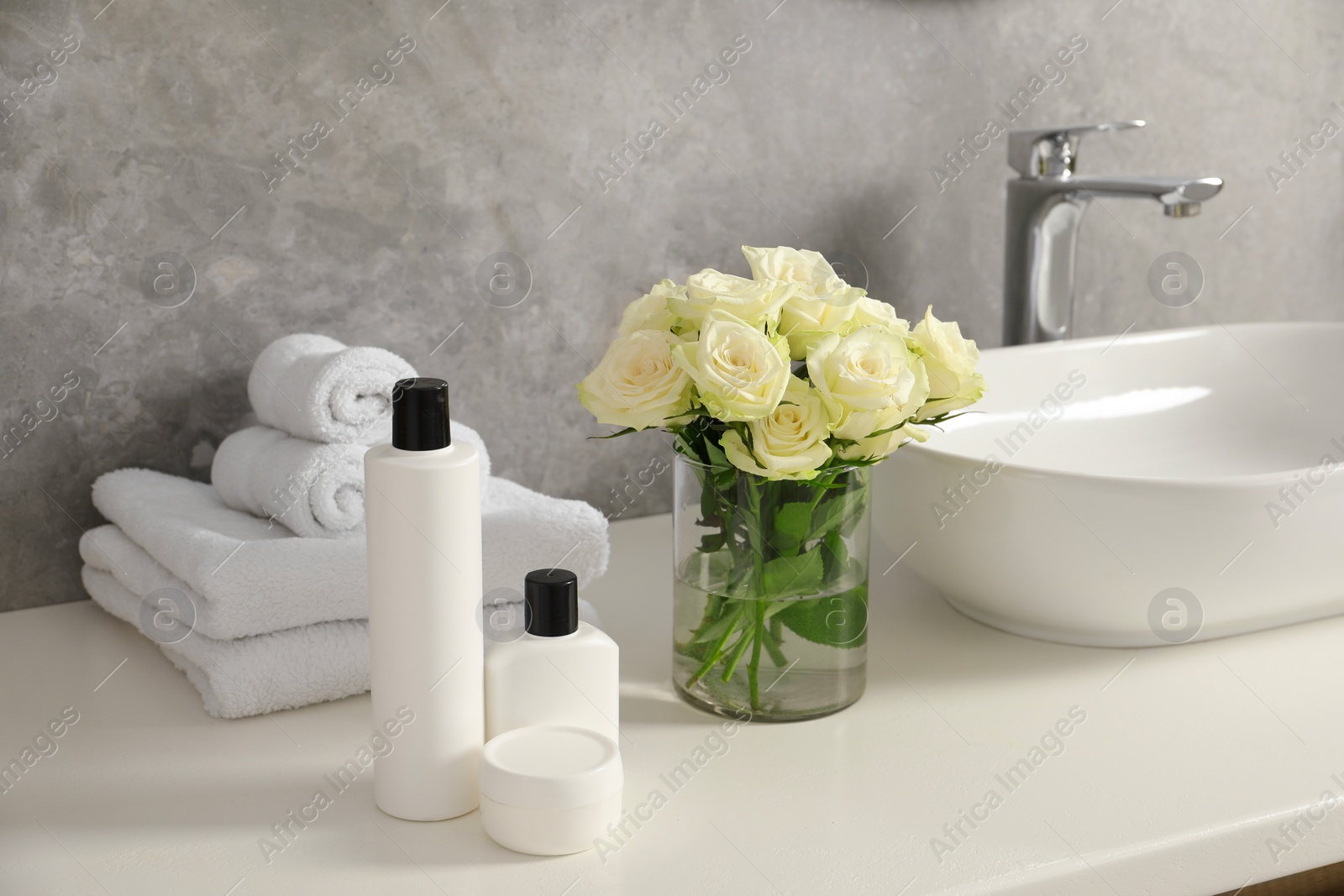 Photo of Beautiful roses and bath accessories near sink in bathroom