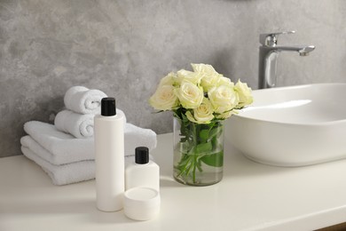 Beautiful roses and bath accessories near sink in bathroom