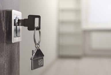 Mortgage and real estate. Open door with key and house shaped keychain against blurred background, space for text