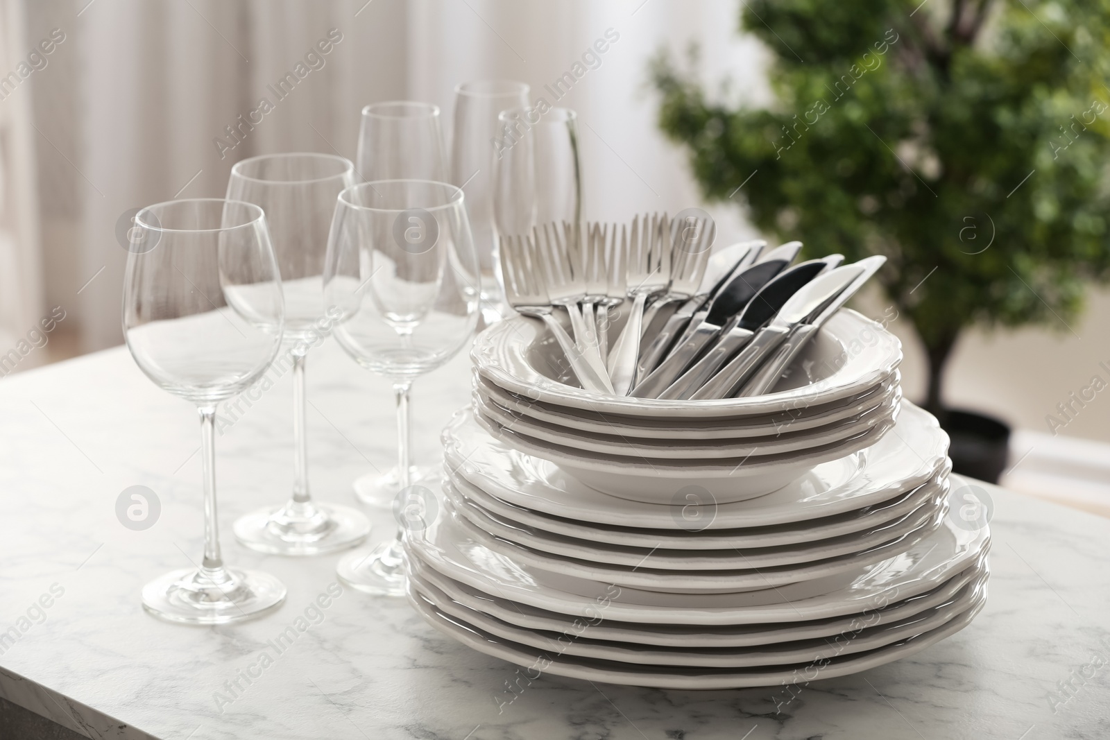 Photo of Set of clean dishware, cutlery and wineglasses on table indoors