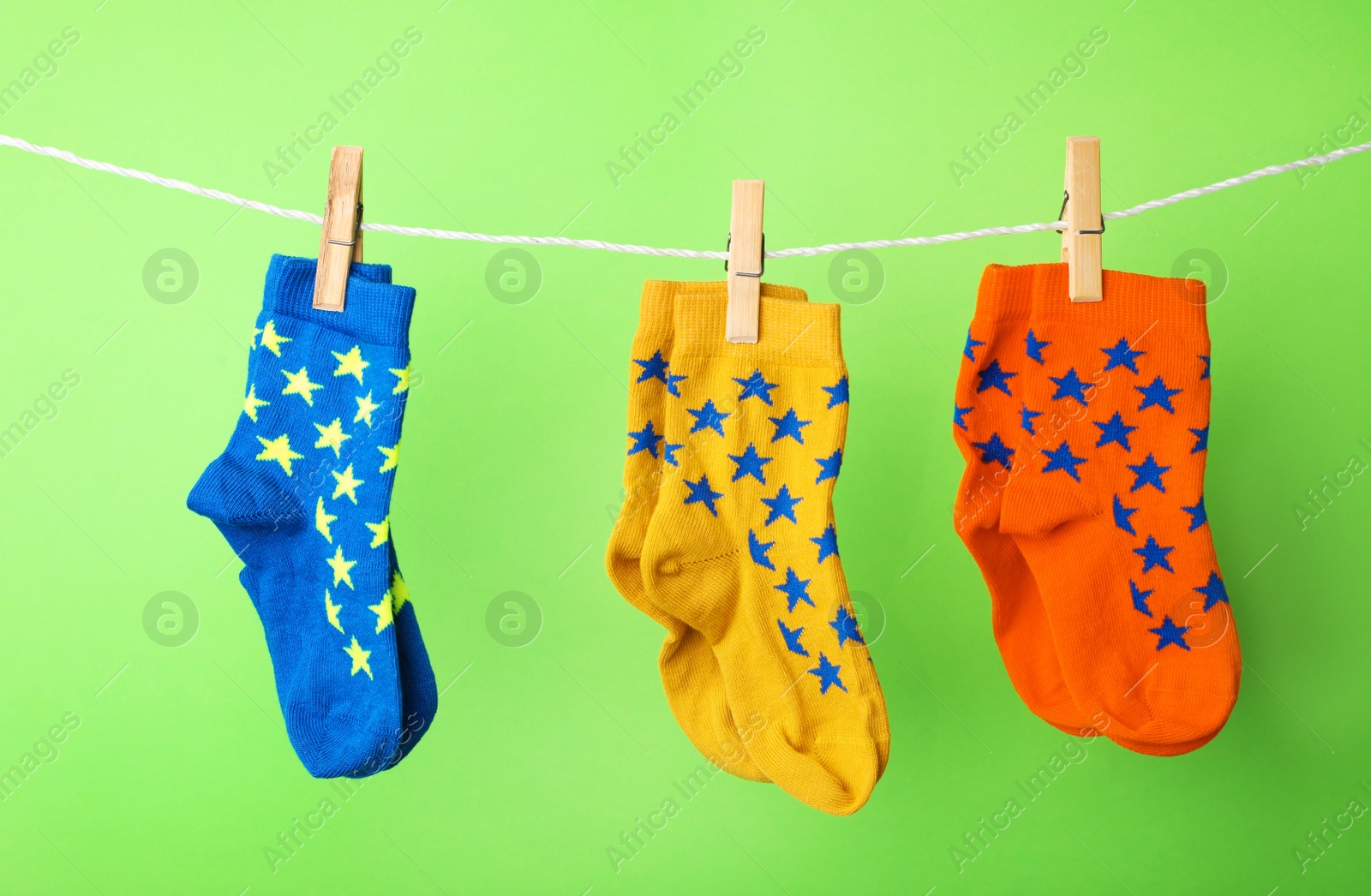 Photo of Cute child socks on laundry line against color background