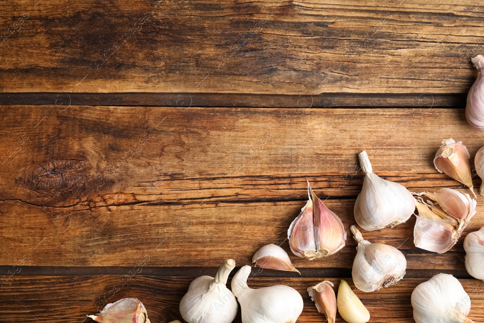 Photo of Fresh organic garlic on wooden table, flat lay. Space for text