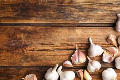 Photo of Fresh organic garlic on wooden table, flat lay. Space for text