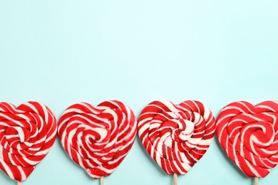 Photo of Sweet heart shaped lollipops on light blue background, flat lay with space for text. Valentine's day celebration