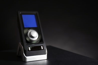 Photo of Remote control of audio speaker system on black table. Space for text