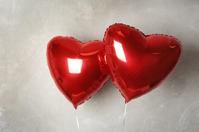 Red heart shaped balloons near grey wall. Valentine's Day celebration